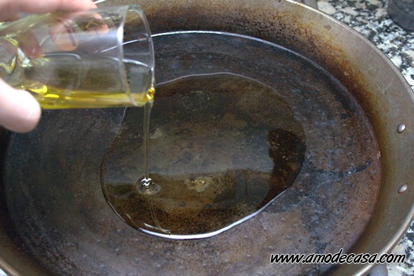 Echando aceite de oliva virgen extra Echar aceite a la paella para dorar el pollo y el conejo